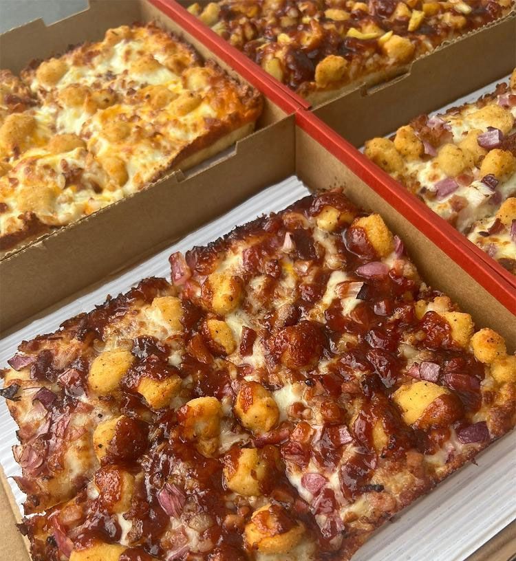 Four pizzas are sitting in a cardboard box