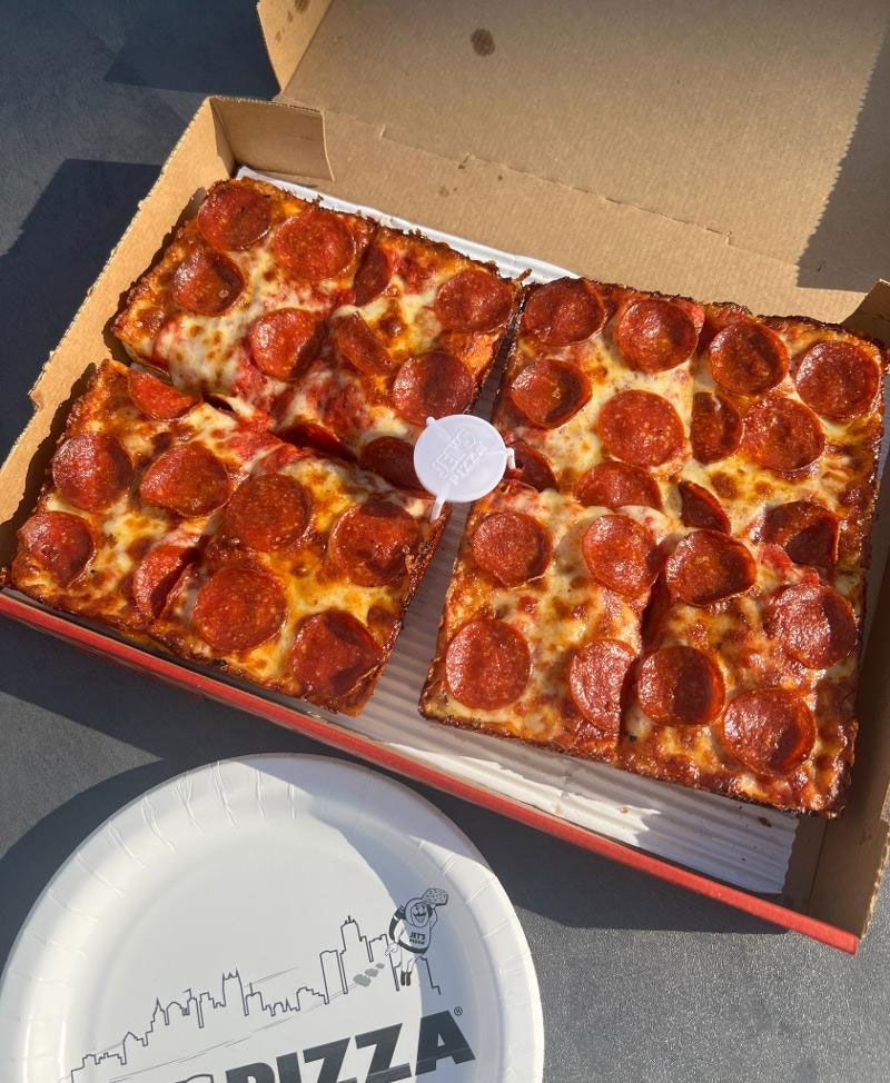 A box of pepperoni pizza next to a paper plate that says pizza