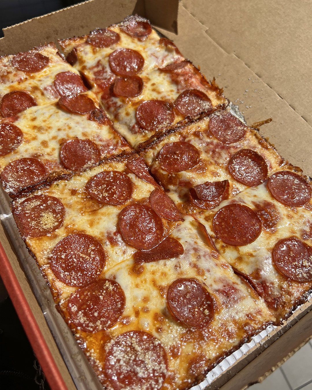 A pizza with pepperoni and cheese is in a box.