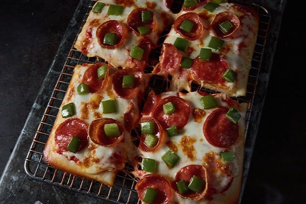A pepperoni pizza is sitting on a cooling rack.