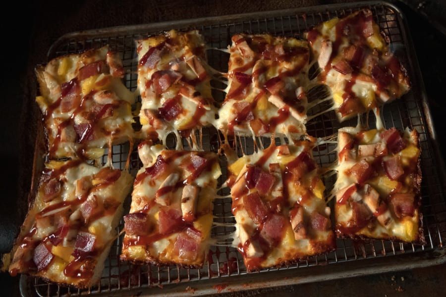 A bunch of pizza slices are sitting on a cooling rack.
