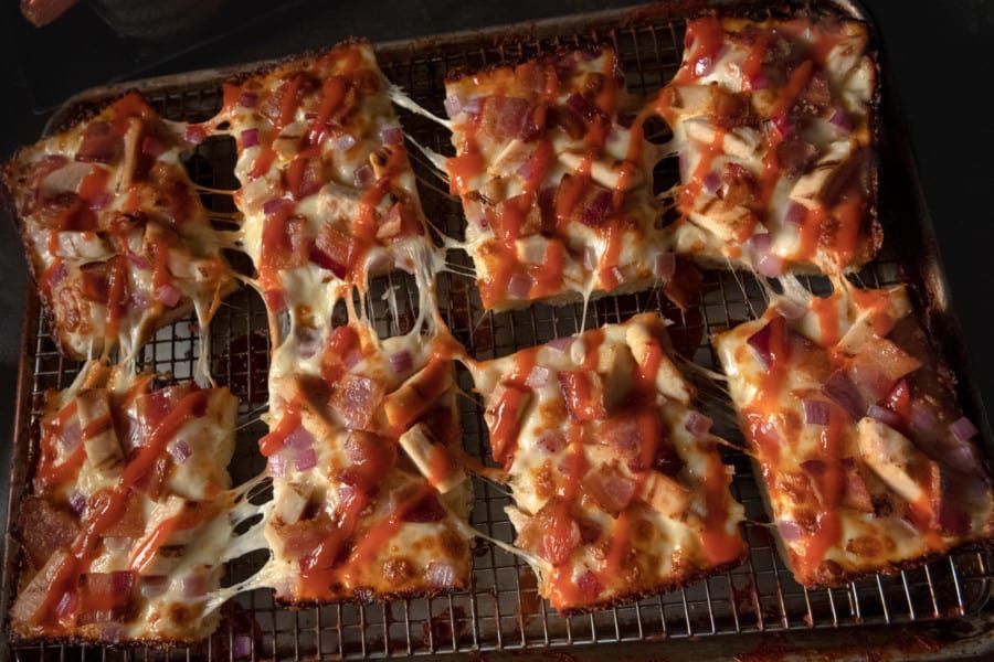 A bunch of pizza slices are sitting on a cooling rack.