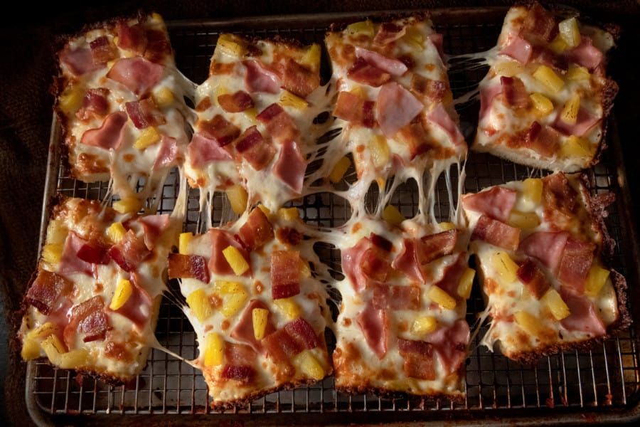 A bunch of pizzas are sitting on a cooling rack.