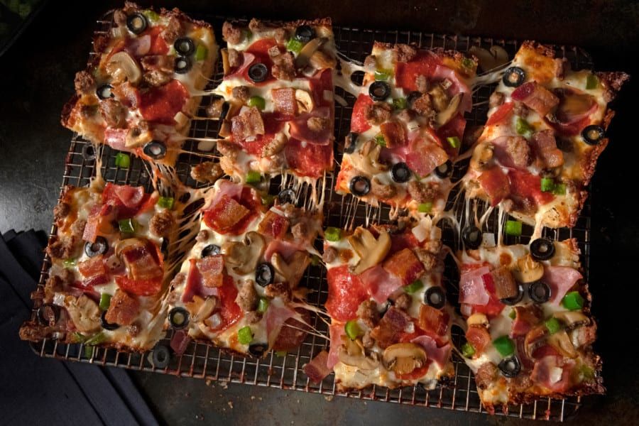 A bunch of pizzas are sitting on a cooling rack