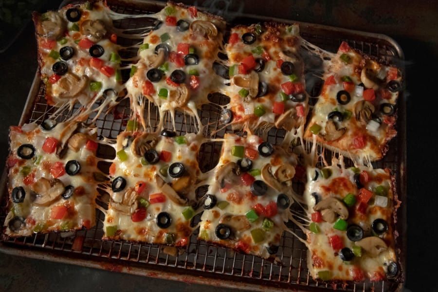 A bunch of pizzas are sitting on a cooling rack.