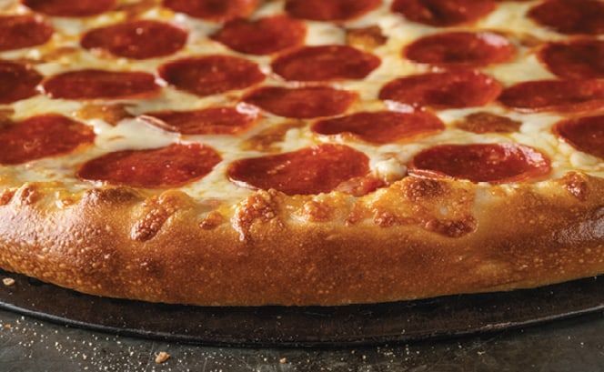 A pepperoni pizza is sitting on a pan on a table.
