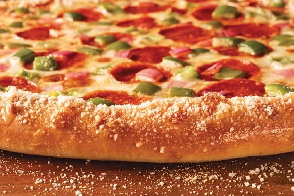 A pizza with garlic and onions is on a pan on a table.