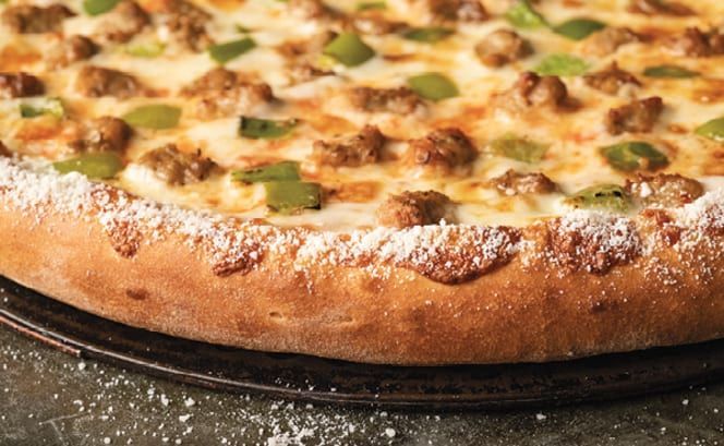 A pizza is sitting on a pan on a table.