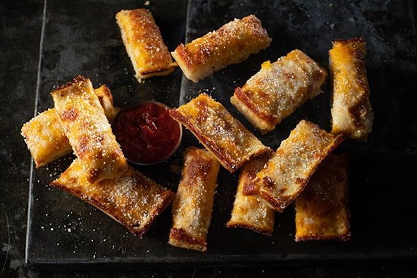 A tray of sticks with ketchup on a table.