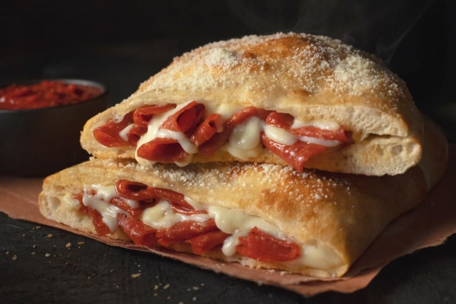 A pepperoni and cheese sandwich is cut in half on a table.
