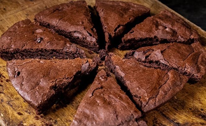 A wooden cutting board topped with sliced brownies.