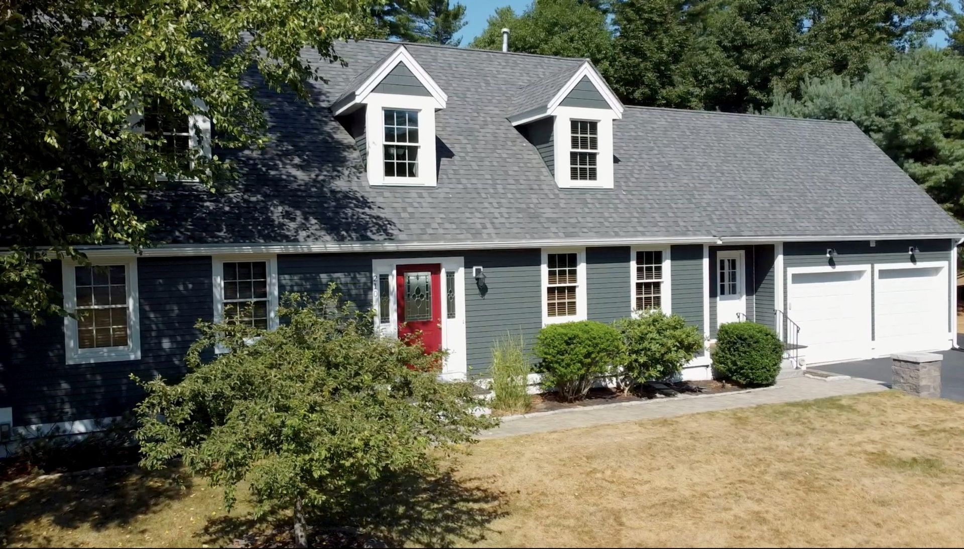 A house with a gray roof and a red door