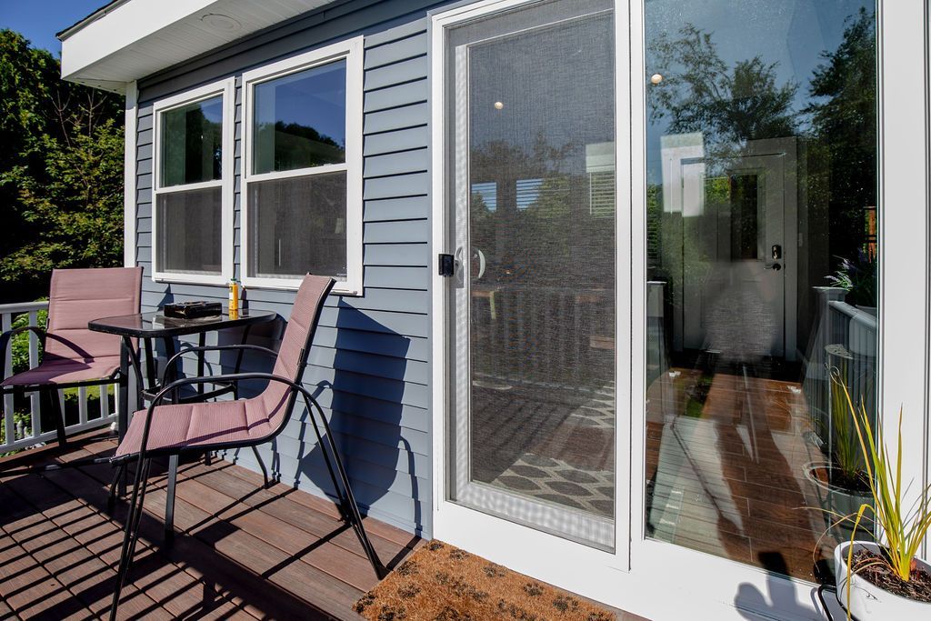 There is a table and chairs on the deck of a house.