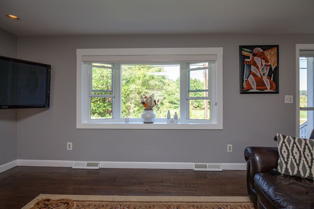 A living room with a large window and a flat screen tv.