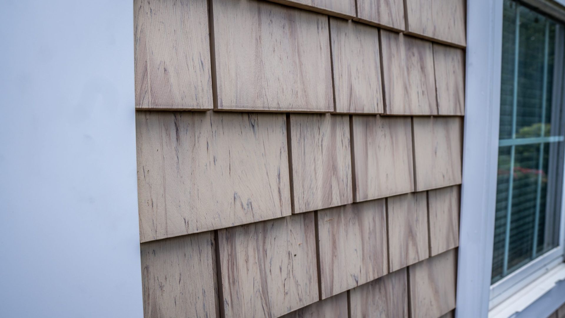 A close up of a wooden siding on a house with a window.