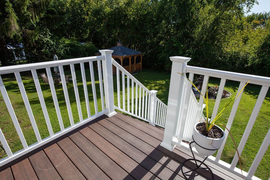 A deck with a white railing and a potted plant on it.