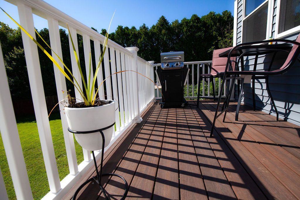A balcony with a white railing and a potted plant