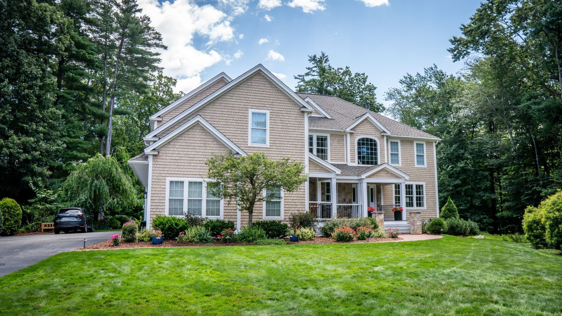 A large house with a large lawn in front of it is surrounded by trees.