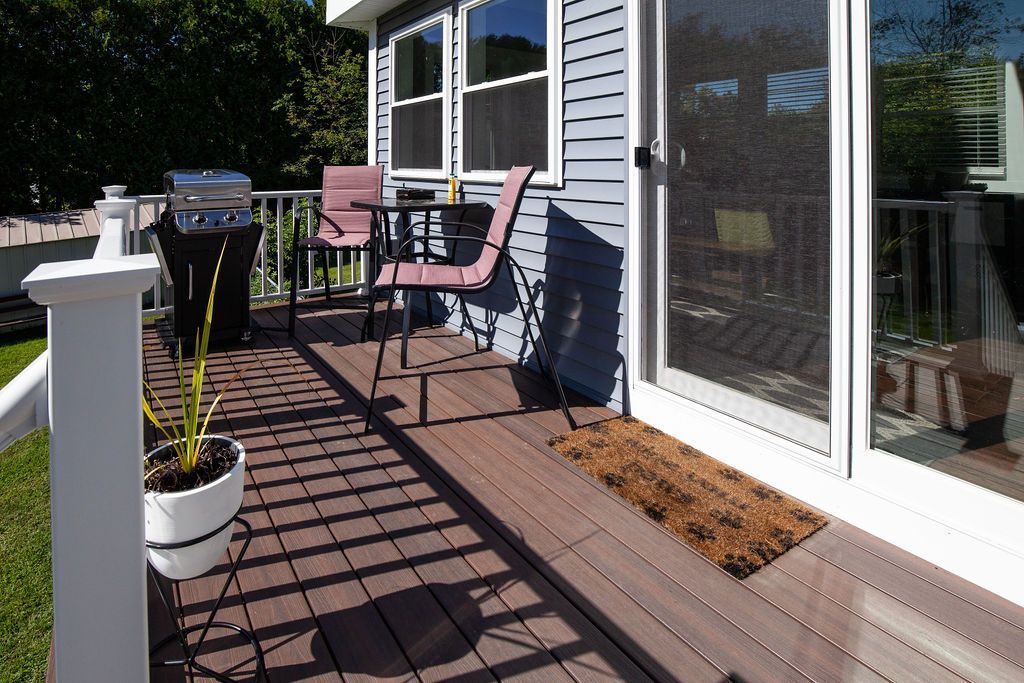 A deck with a table and chairs in front of a house