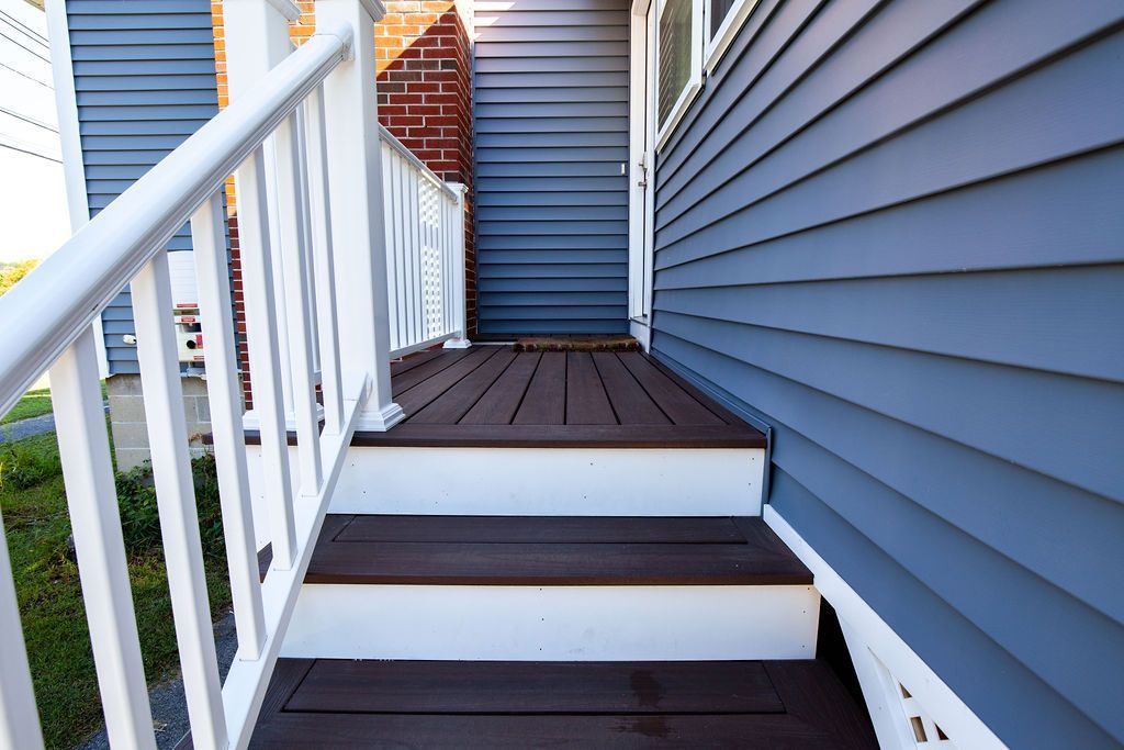 A porch with wooden steps and a white railing