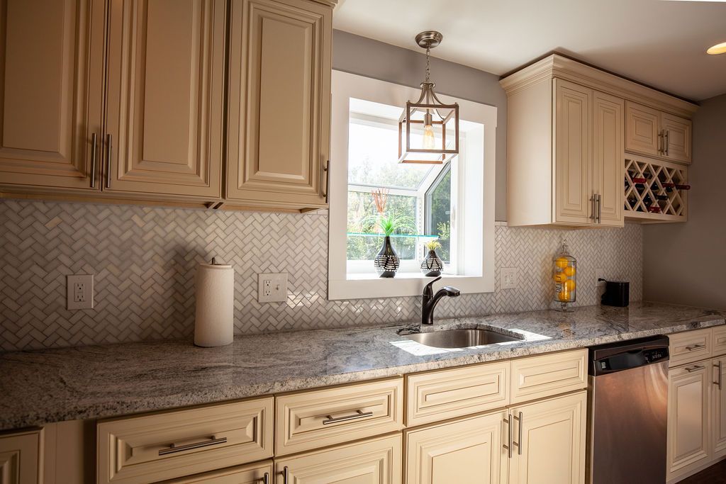 A kitchen with white cabinets , granite counter tops , a sink , and a window.