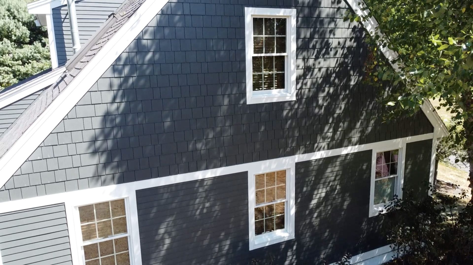 A black house with white trim and a slate roof