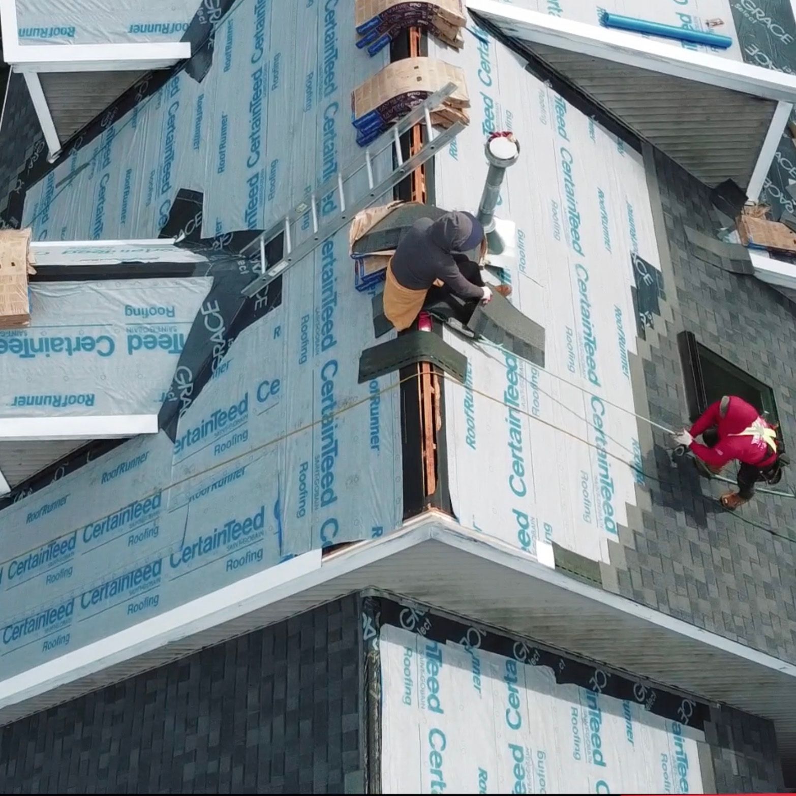 An aerial view of a building being built with a roof covering that says certified