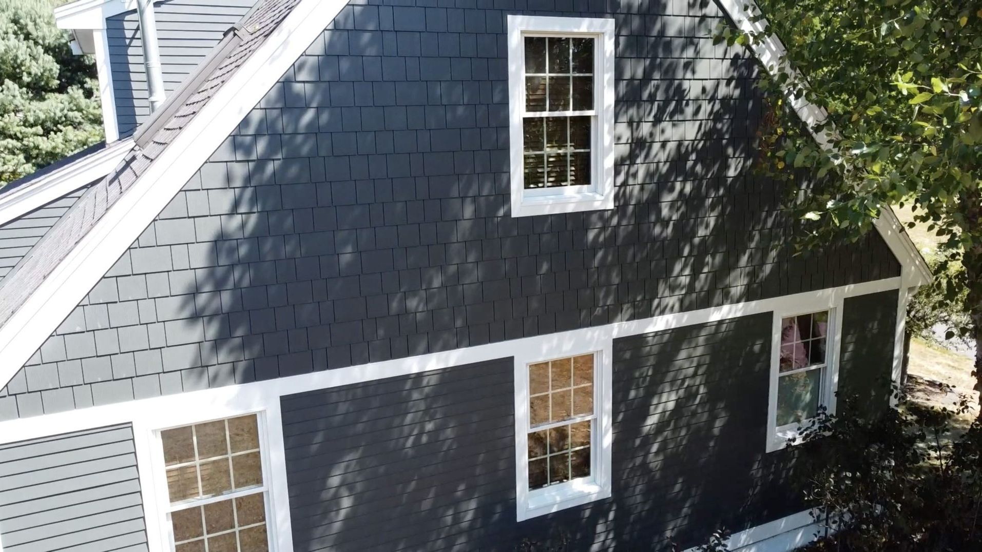 A large house with a lot of windows is surrounded by trees and bushes.