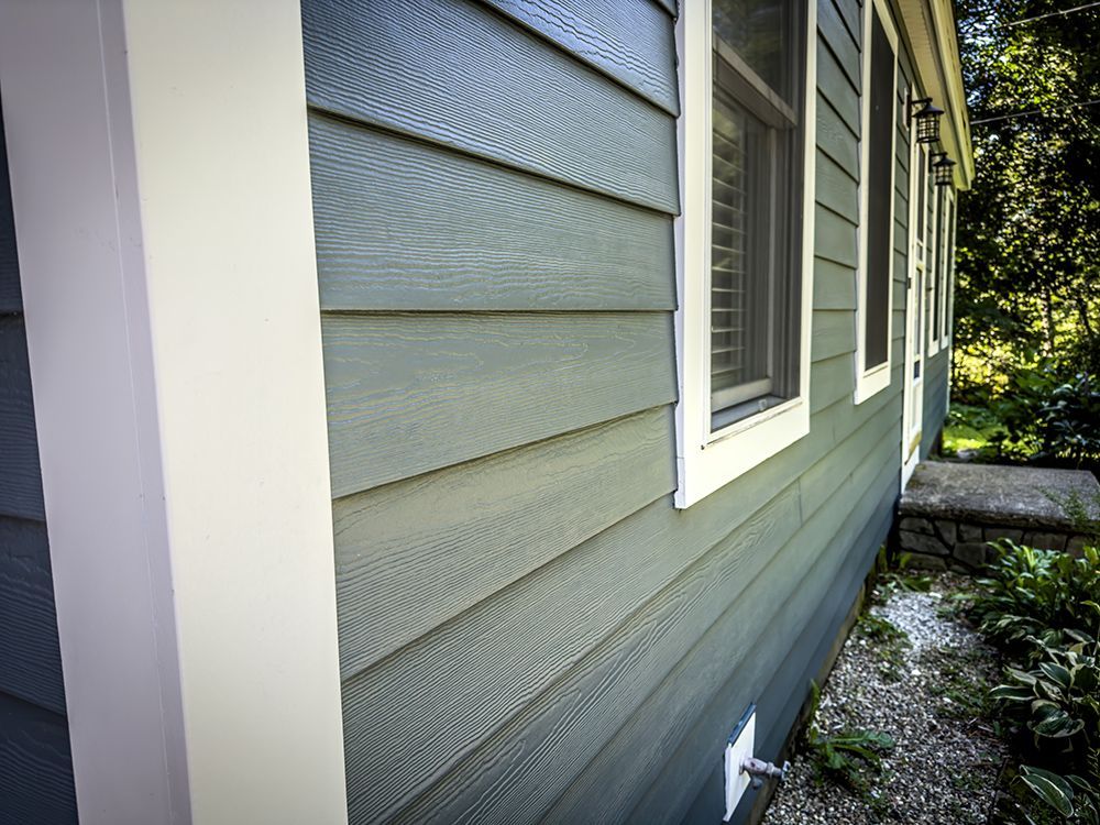 The side of a house with a gray siding and white trim