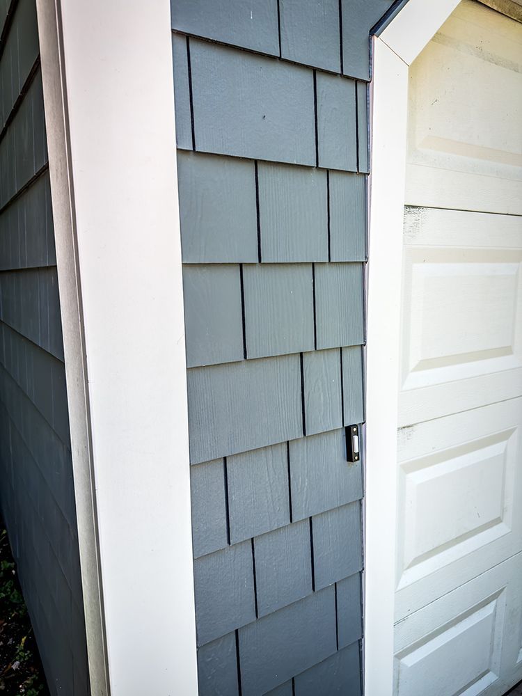 A corner of a house with a white garage door