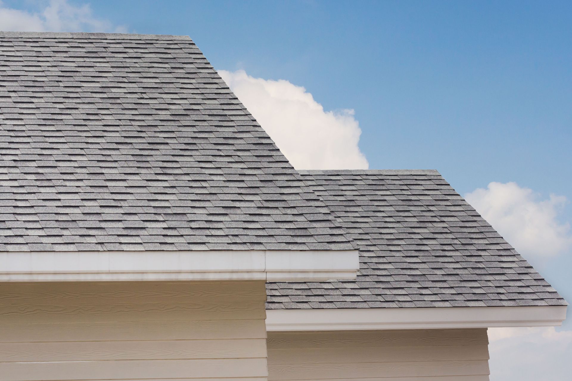 Gray shingled roof against a blue sky with clouds