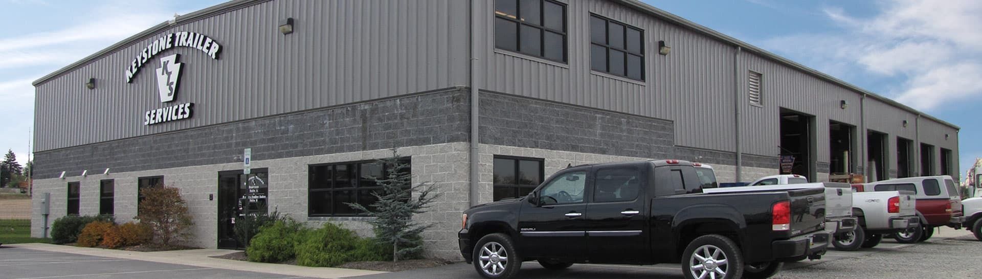 A commercial warehouse building with "KENTUCKY" and "AGRITECH" signage, parked trucks in front, and a blue sky overhead.