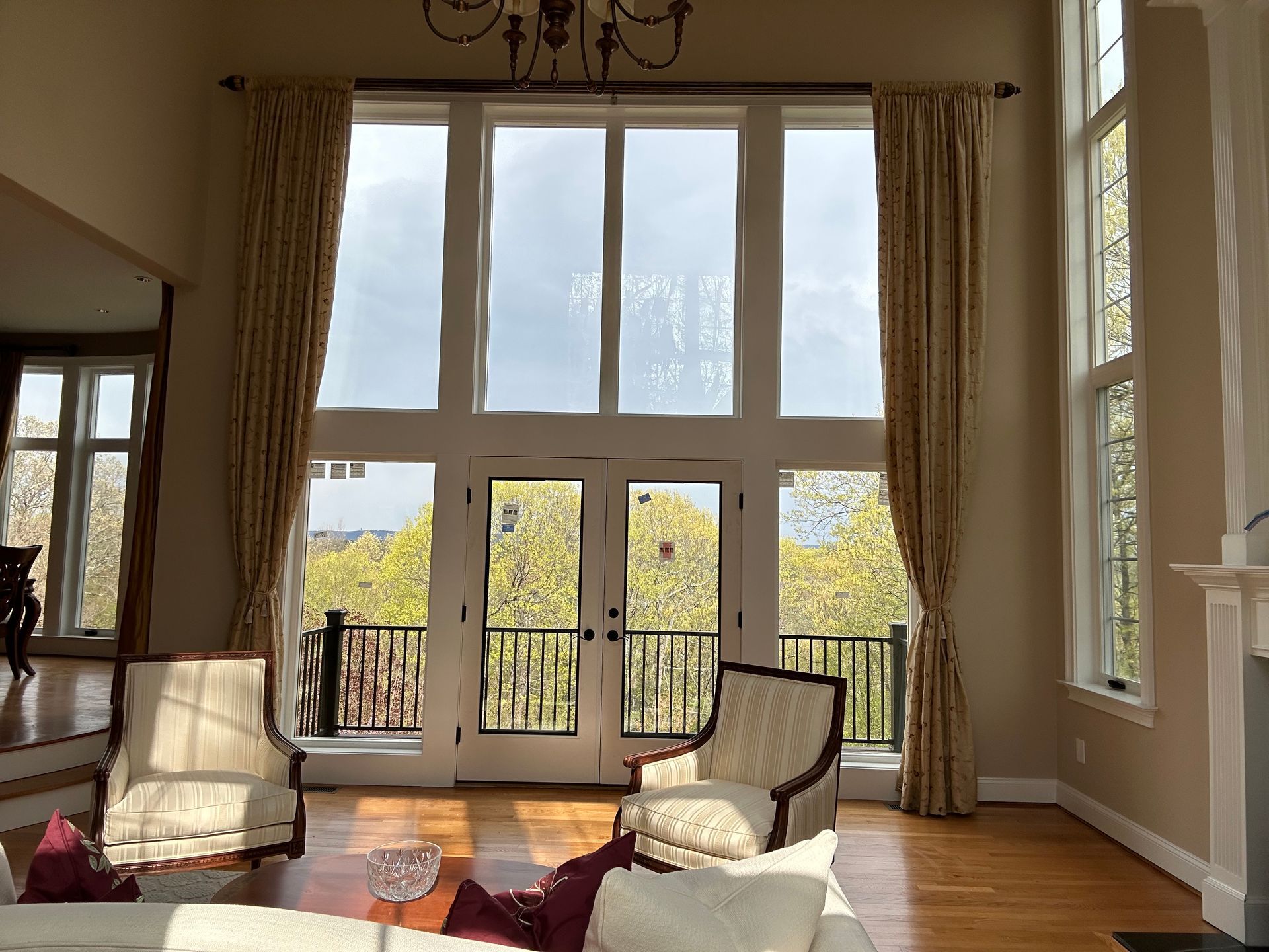 Sunlit living room with tall windows, neutral chairs, and a city view