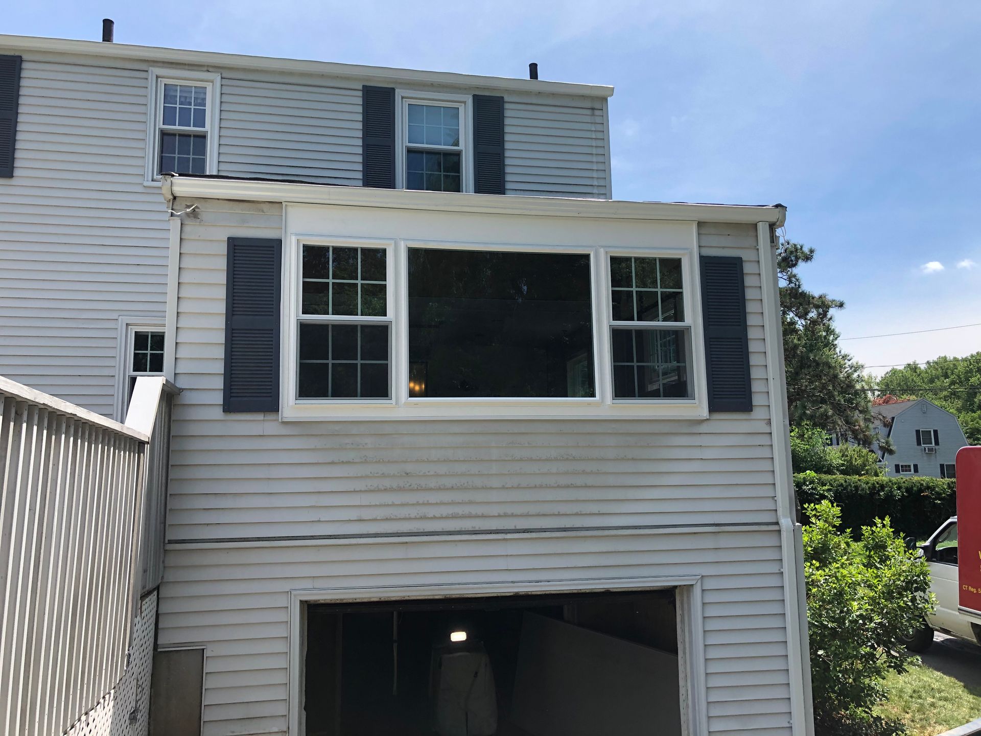 White house exterior with an enclosed rear porch and basement garage opening