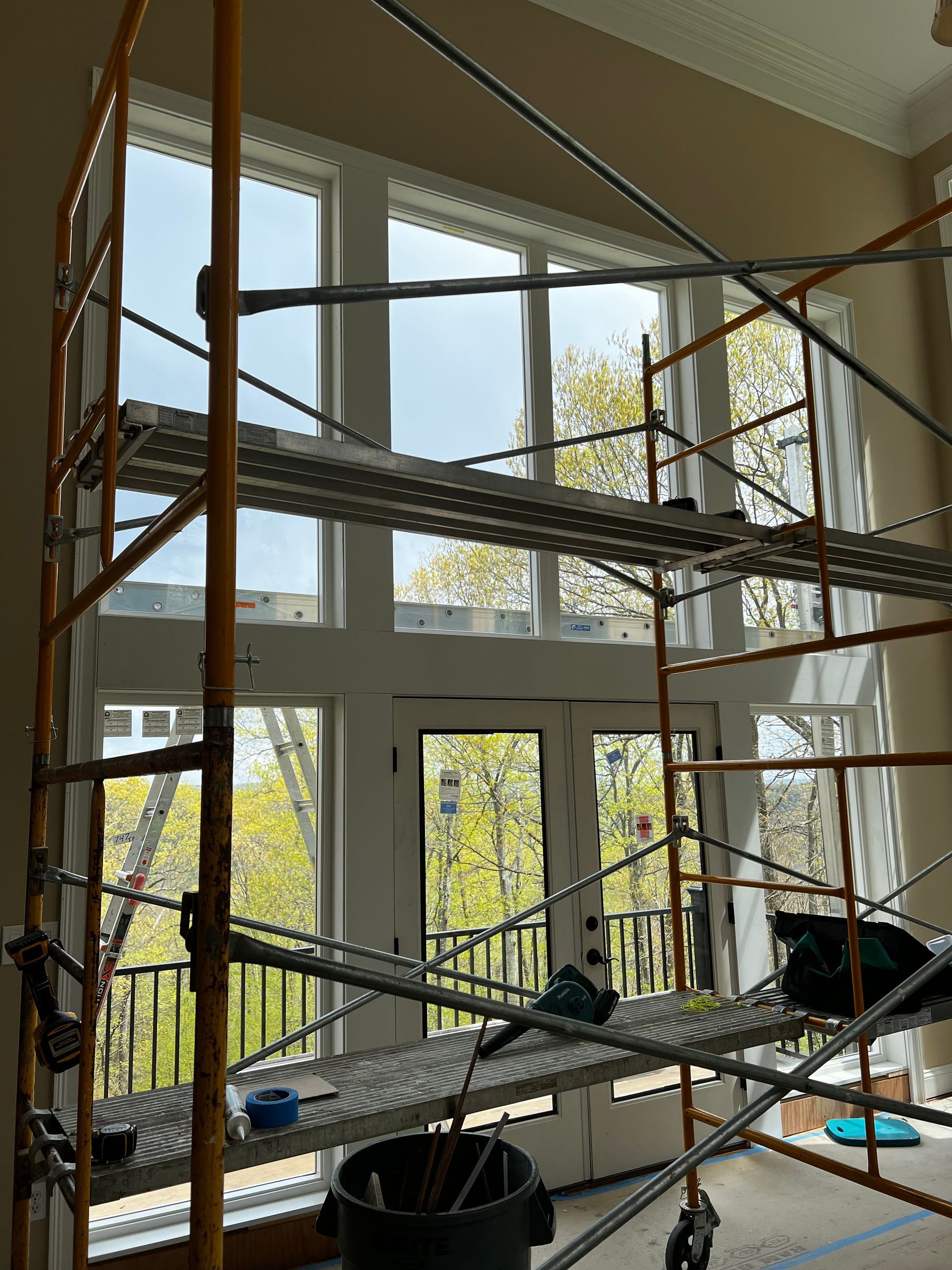 Scaffolding inside a bright atrium with large windows and sunlight filtering through.