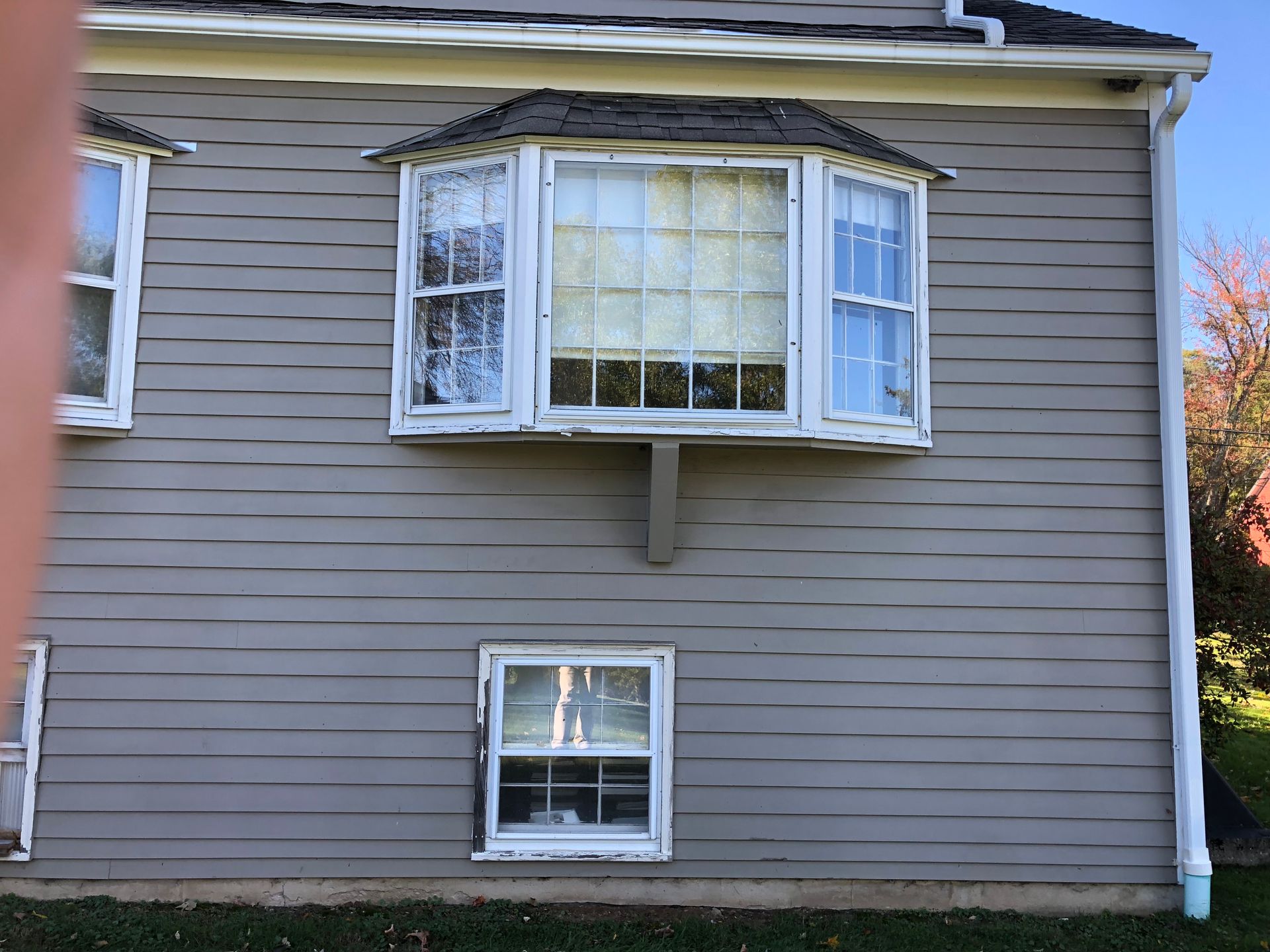 Gray house exterior with a bay window upstairs and a small window below.