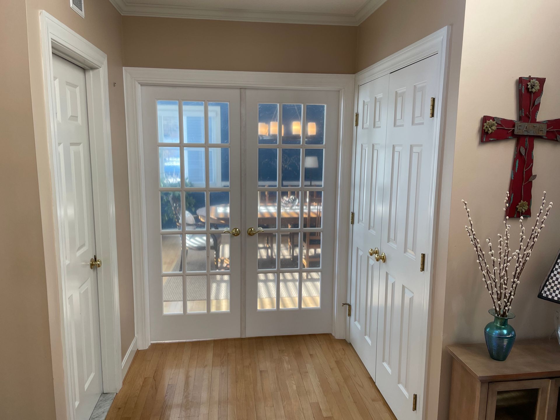 Hallway with white French doors, wood floor, and decorative wall cross.