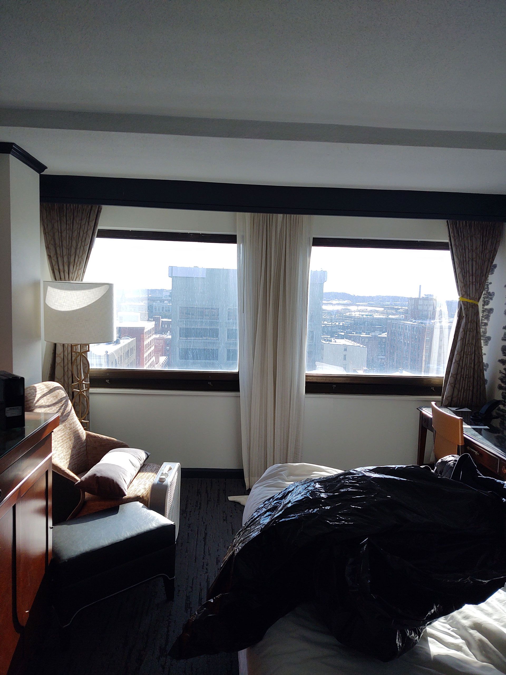 A hotel room with a bed, a chair and a lamp