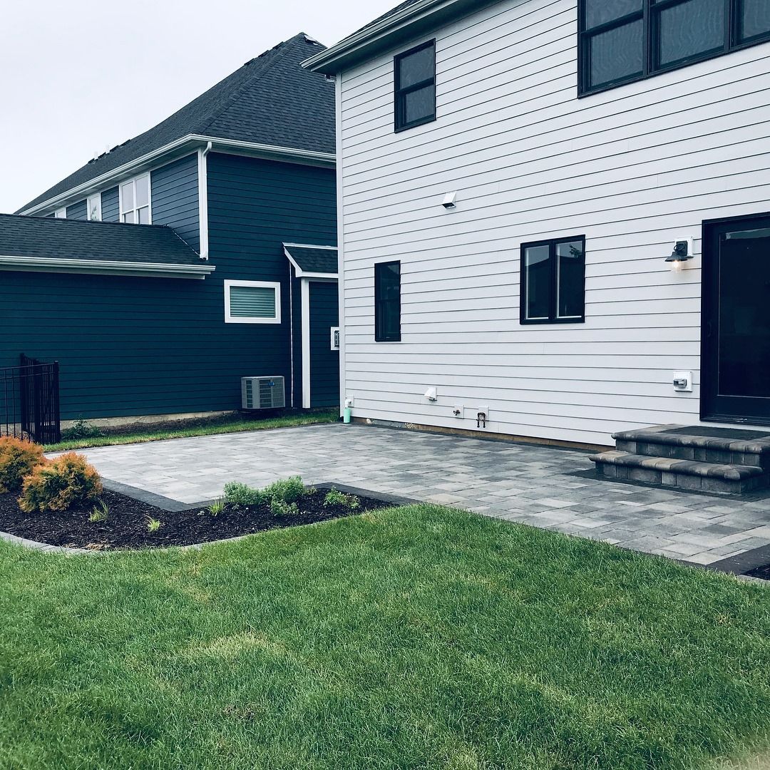 A white house with a blue roof and a patio in front of it.