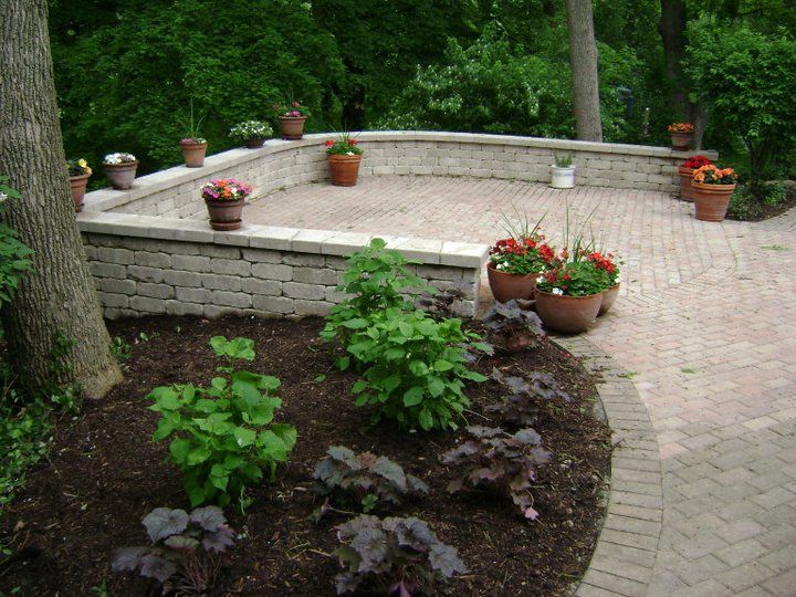 A brick patio with potted plants and trees in the background
