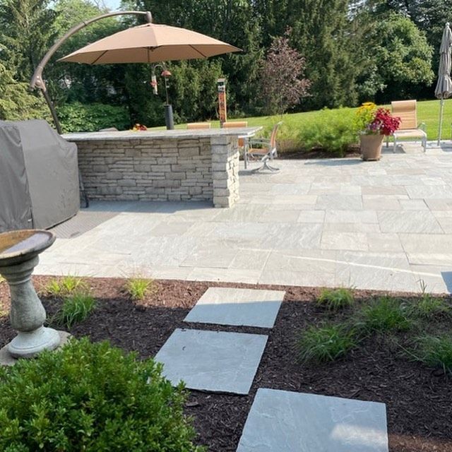 A patio with a large umbrella and a grill