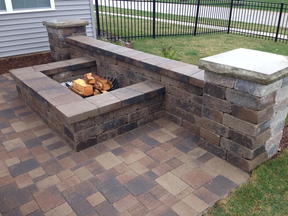 A fire pit is built into the side of a brick wall.