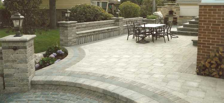 A patio with a table and chairs in the backyard of a house.