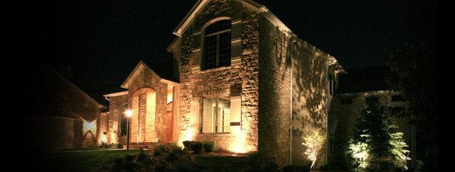 A large stone house is lit up at night.