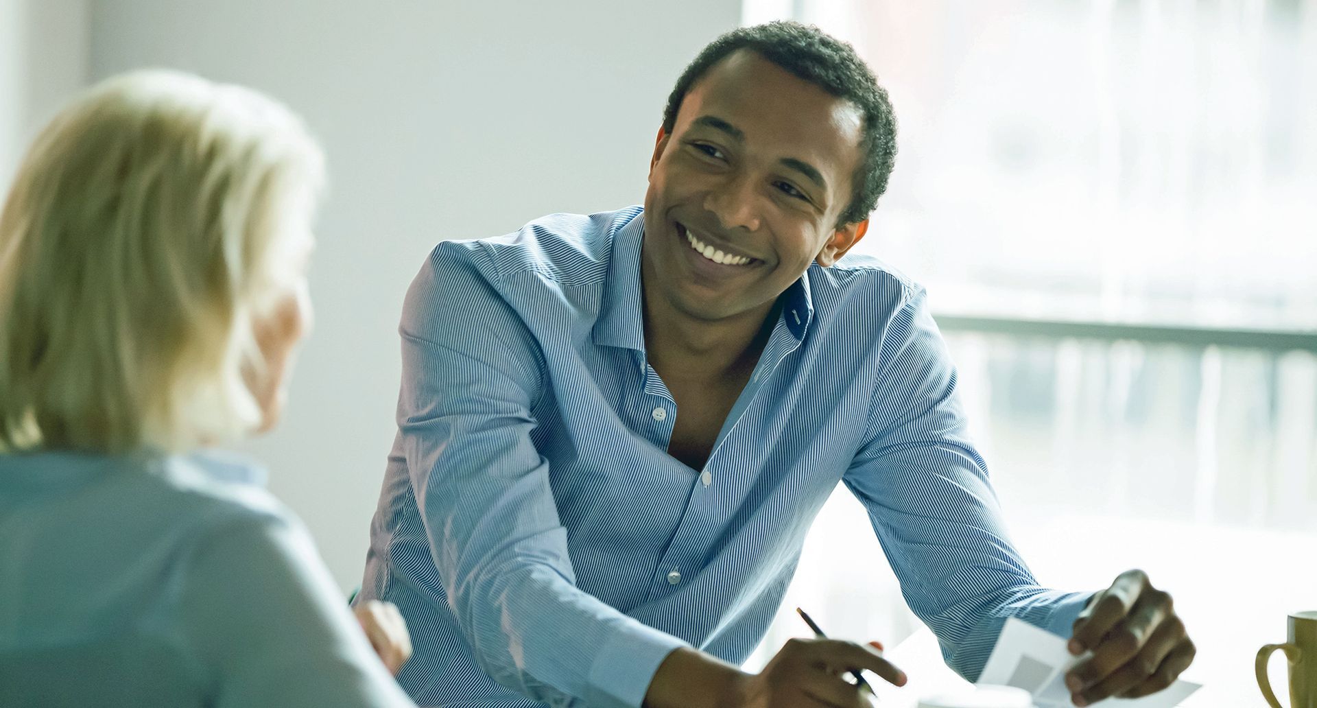 Man in distress, sitting on a couch in therapy session; therapist gesturing, tissues on table.