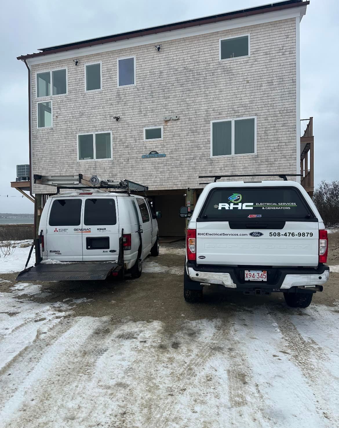 Two white vans are parked in front of a building in the snow.