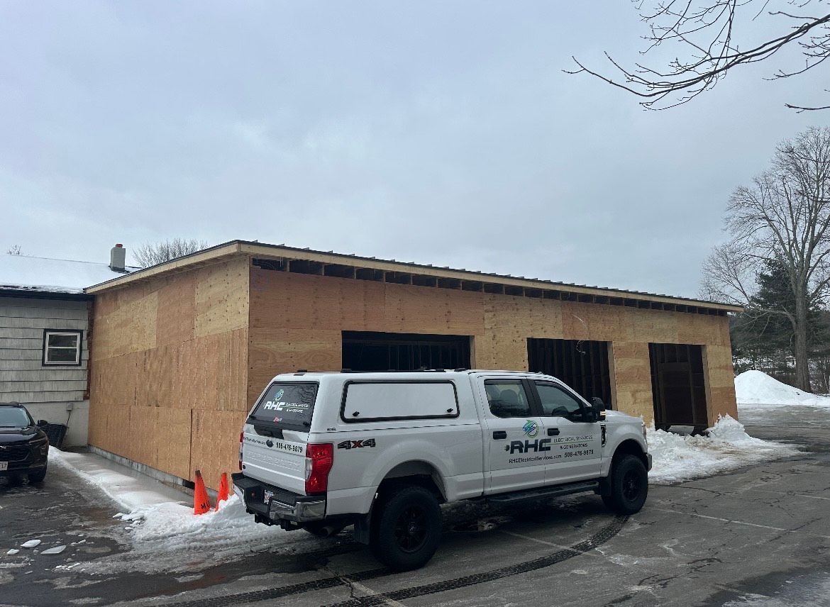 A white truck is parked in front of a garage under construction.