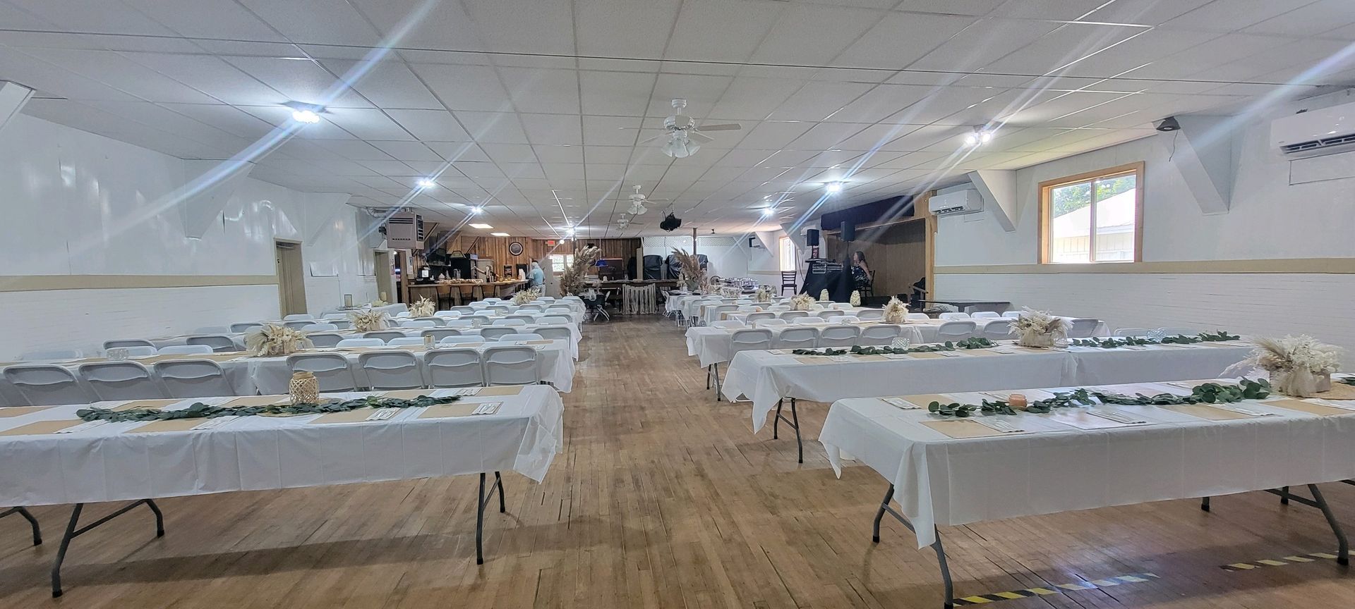 A large room filled with tables and chairs set up for a wedding reception.