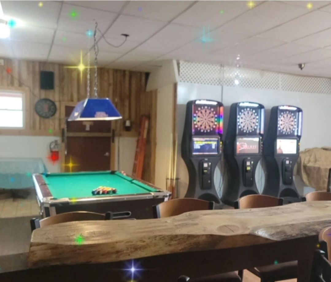A pool table and dart machines in a room