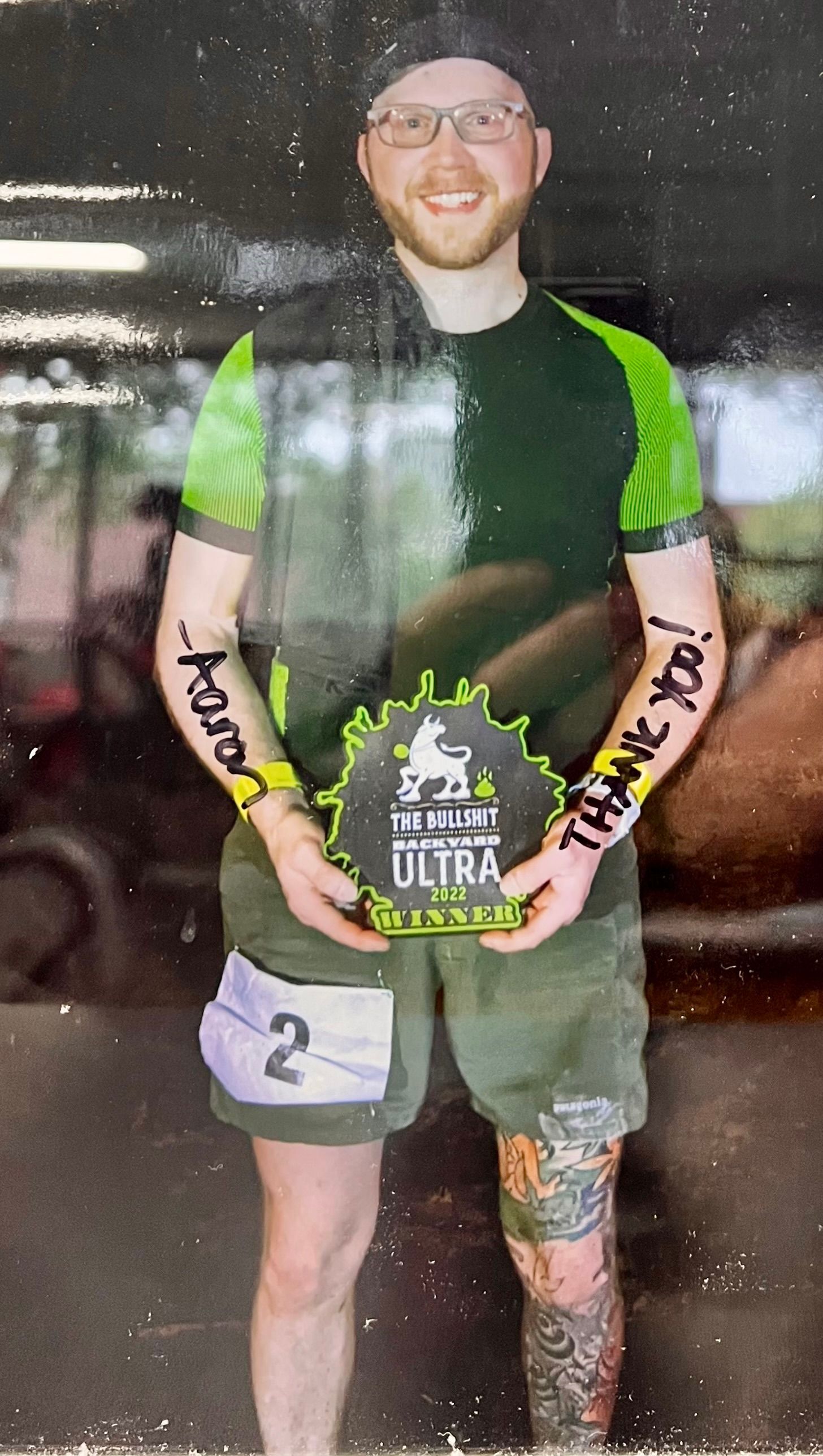 A man with tattoos on his arms is holding a trophy.